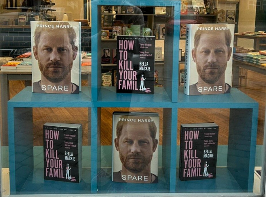 Livro de memórias 'O que sobra', do príncipe Harry, ao lado do romance 'Como matar a tua família', de Bella Mackie, em vitrine de livraria no Reino Unido