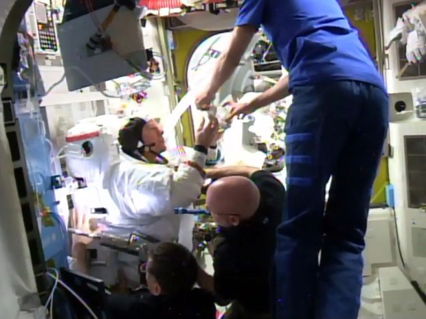 Imagem feita a partir de um vídeo da Nasa mostra membros da Estação Espacial Internacional inspecionando o traje do astronauta Timothy Kopra (esquerda), após ele ter relatado problemas durante caminhada espacial na sexta (15) (Foto: NASA via AP)