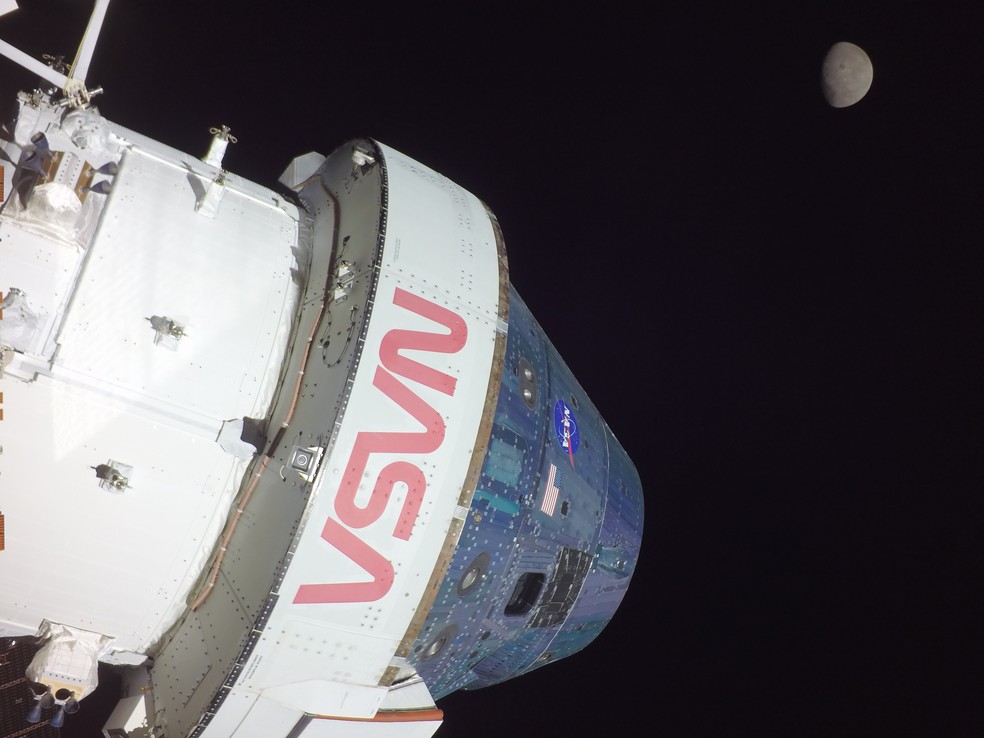 Câmera na ponta de uma das asas do painel solar da cápsula Orion mostra a espaçonave e Lua no mesmo enquadramento.. — Foto: Nasa