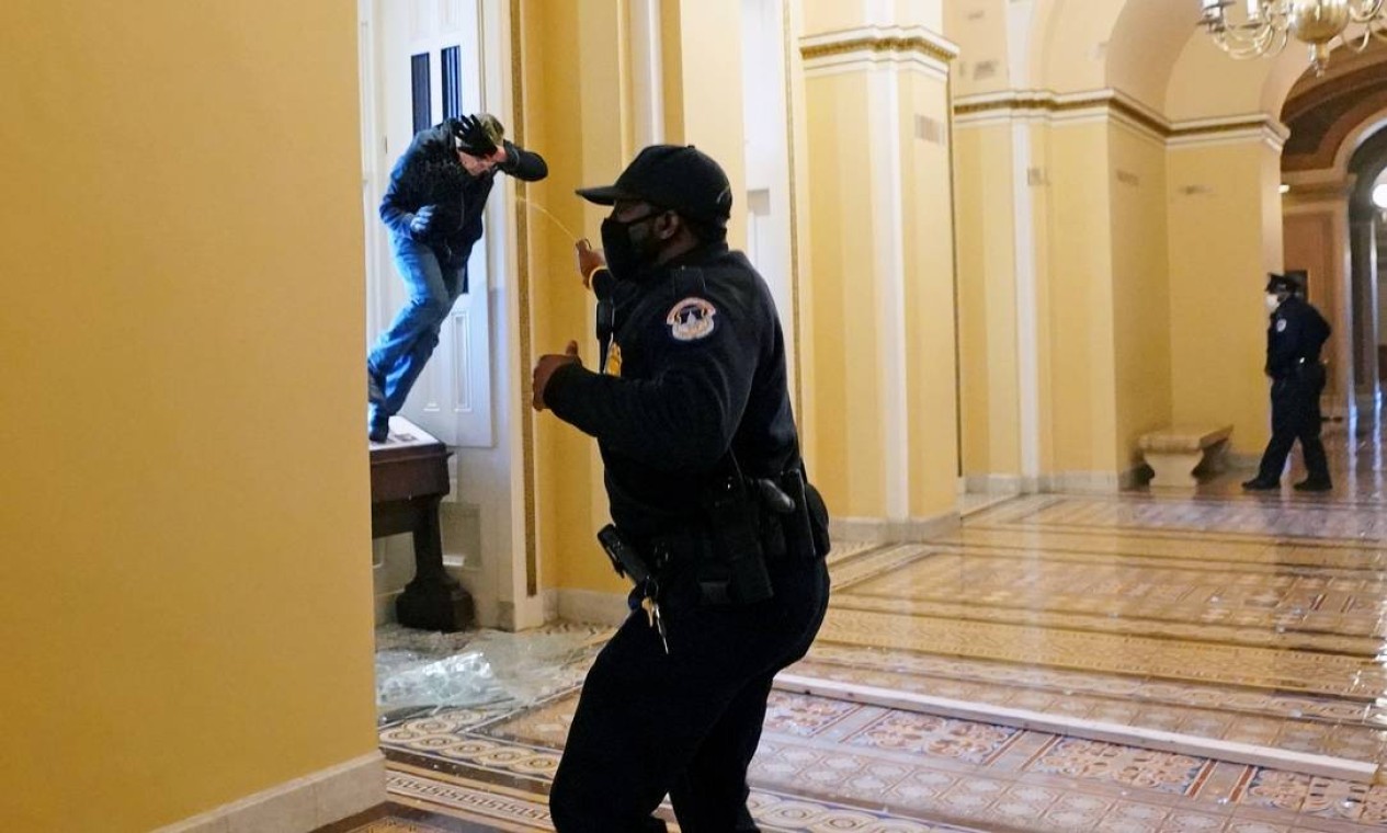 Policial do Capitólio atira spray de pimenta em um manifestante que tenta entrar no prédio do Congresso  — Foto: POOL / REUTERS