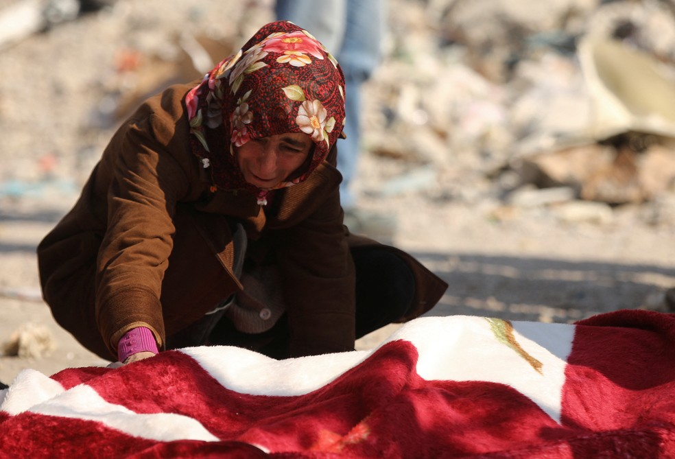 Mulher chora sobre corpo de vítima encontrada em escombros causados por terremoto na Turquia — Foto: Reuters