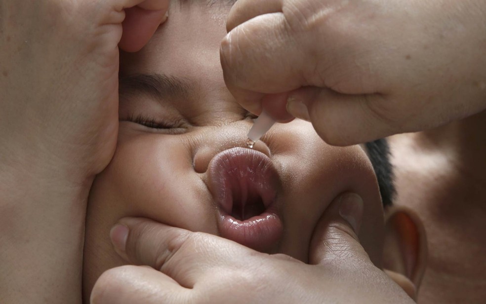 Funcionário da área de saúde aplica vacina oral em uma criança em Makati, a leste de Manila, nas Filipinas. (Foto: Bullit Marquez/AP)