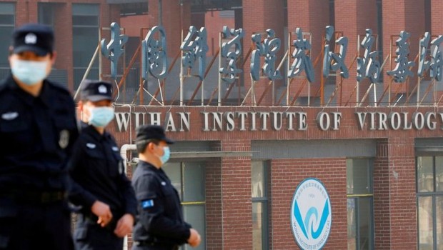 BBC Agentes de segurança vigiam área externa do Instituto de Virologia de Wuhan durante a visita de equipe da OMS em fevereiro (Foto: Reuters via BBC)
