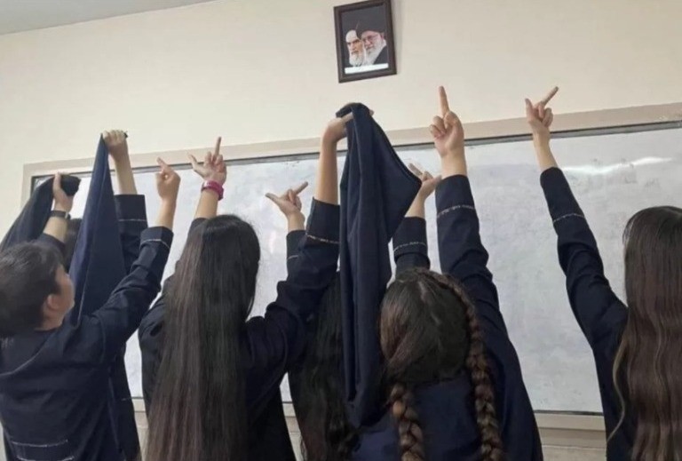 Em sala de aula, estudantes sem hijab mostram o dedo do meio para foto dos aiatolás Khamenei e Ruhollah Khomeini (Foto: Reprodução/Twitter)