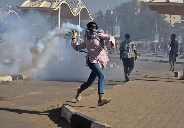Um manifestante arremessa uma lata de gás lacrimogêneo durante um protesto exigindo o fim do regime militar, em Cartum, Sudão, em 30 de dezembro de 2021 (Foto: FAIZ ABUBAKR MOHAMED via BBC)