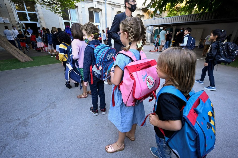 Crianças com mochilas esperam em fila em um parquinho de uma escola primária em Montpellier, na França, no dia 1º de setembro — Foto: Pascal Guyot / AFP