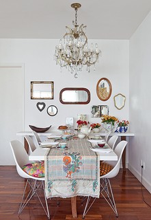A sala de jantar da designer Ana Morelli tem paredes e móveis brancos, mas está longe de ser um ambiente neutro. Ele ganhou charme com vários espelhos, bules com flores e xícaras coloridas
