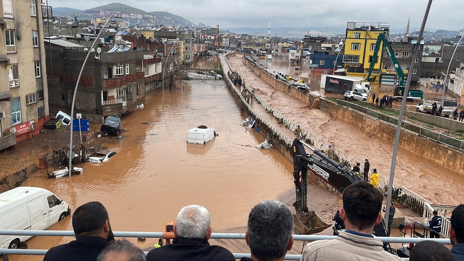 Pessoas em um ponto alto olhando para as águas da enchente em Sanliurfa, sudeste da Turquia, em 15 de março de 2023