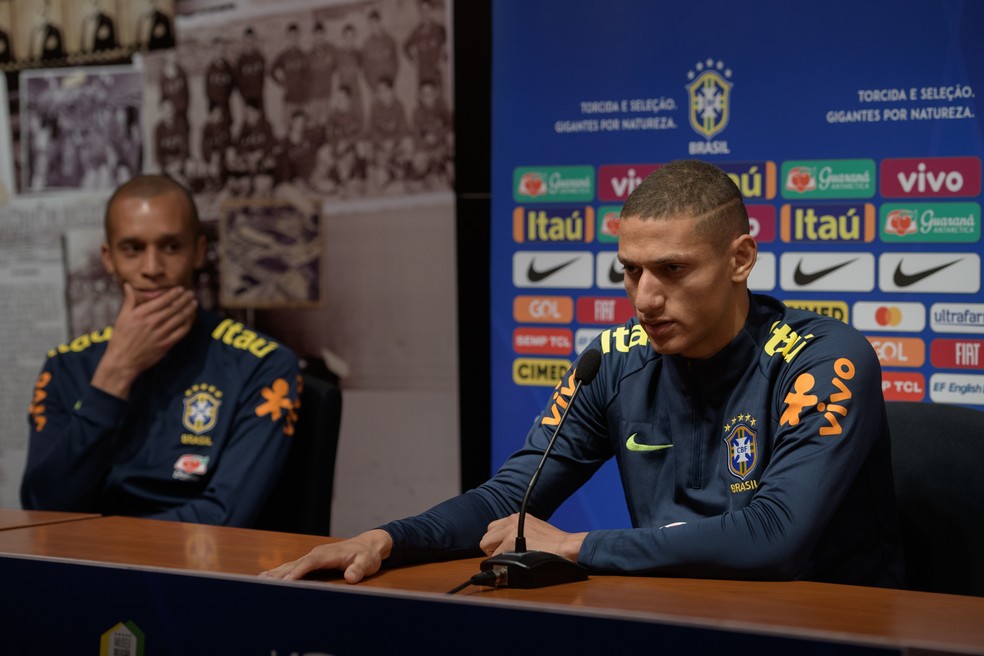 Miranda, de 34 anos, observa a entrevista de Richarlison, 13 anos mais jovem — Foto: Pedro Martins/Mowa Press