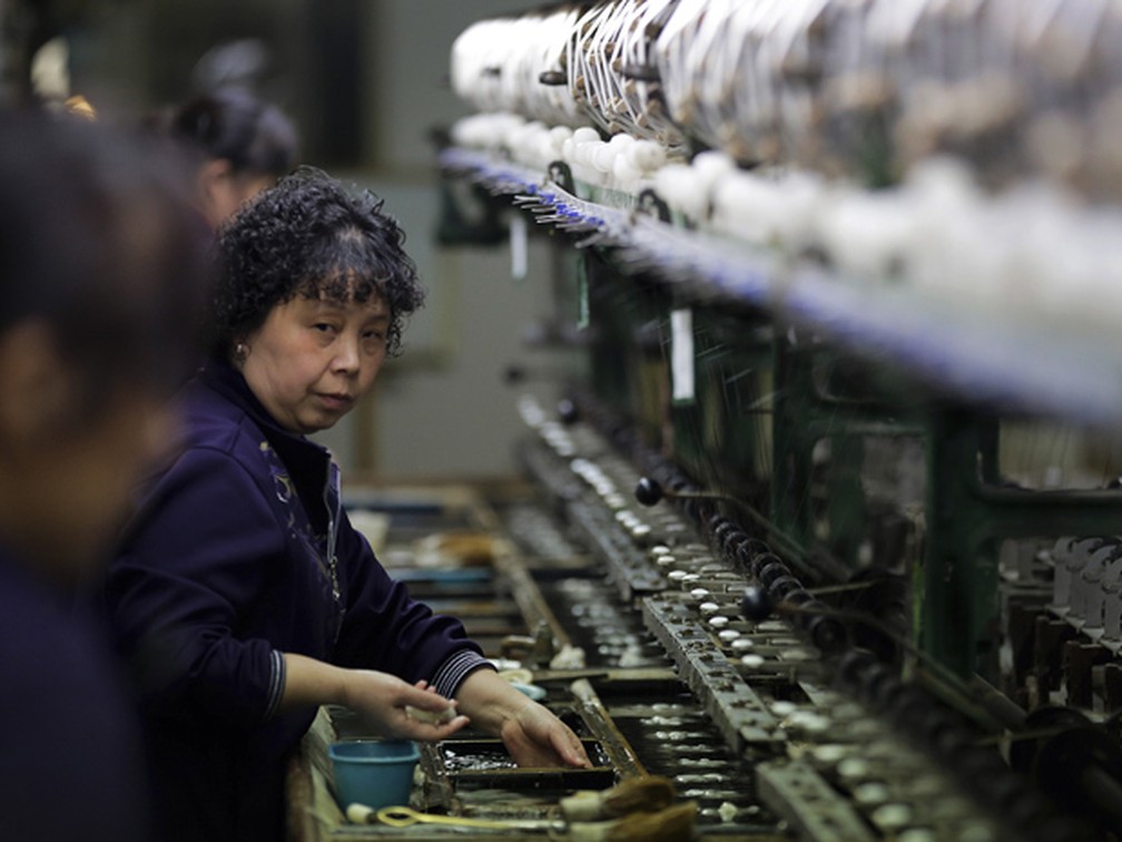 Mulher trabalha em fábrica de seda na província chinesa de Jiangsu.  — Foto: Andy Wong/AP