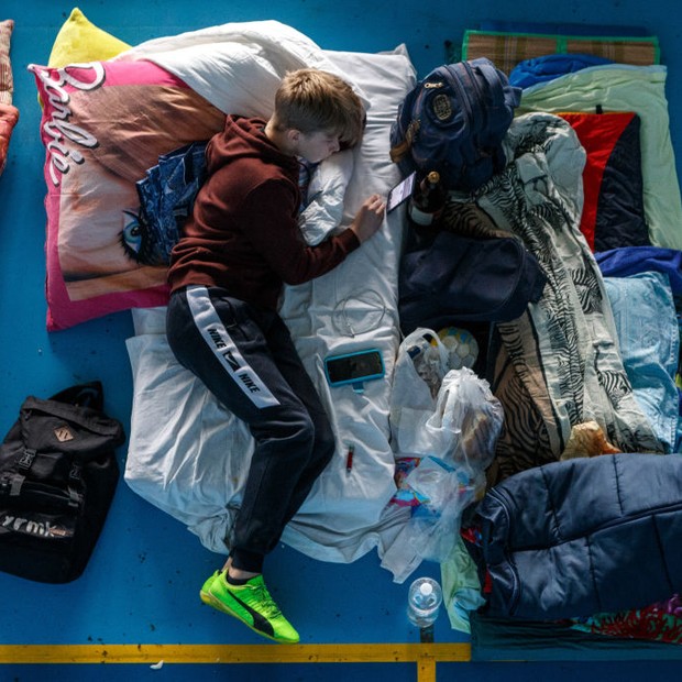 UZHHOROD, UKRAINE - MARCH 7, 2022 - A boy lies on the mattress browsing his phone in one of the sports complexes accommodating internally displaced people in Uzhhorod, western Ukraine, on March 7, 2022. (Photo credit should read Serhii Hudak/ Ukrinform/Fu (Foto: Future Publishing via Getty Imag)