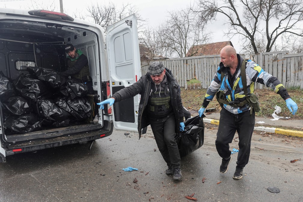 Guerra na Ucrânia - voluntários recolhem corpos de civis mortos por soldados russos em Bucha, segundo moradores.  — Foto: REUTERS/Stringer