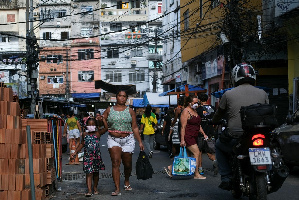 21 de abril: mulher e criança andam de mãos dadas com máscaras protetoras contra a Covid-19 na Favela da Rocinha, no Rio de Janeiro. — Foto: Ricardo Moraes/Reuters