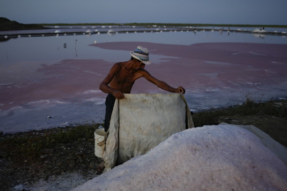 Homem cobre pilha de sal nas salinas de Pampatar, na Ilha Margarita, Venezuela
