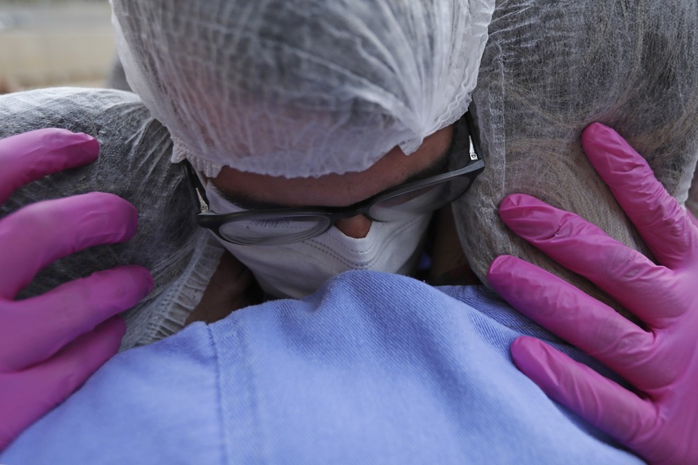 Profissionais de saúde se abraçam enquanto comemoram as altas dos três últimos pacientes do hospital de campanha para Covid-19 no Estádio Mané Garrincha, em Brasília, no dia 15 de outubro. — Foto: Eraldo Peres/AP