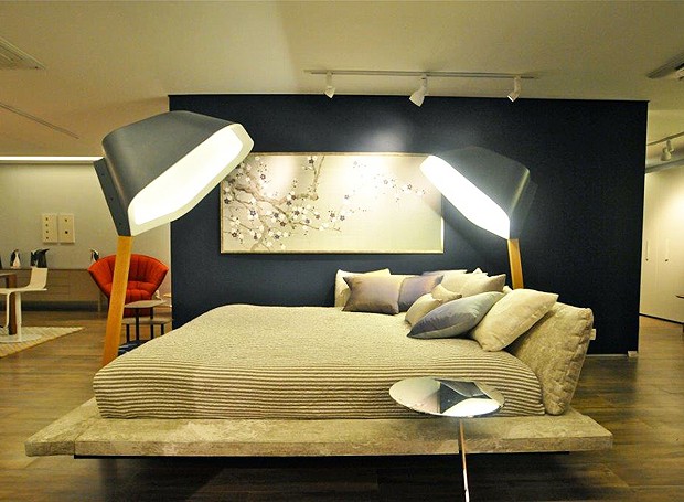 No espeço de René Fernandes, a espaçosa cama parece estar apoiada sobre um tablado e é emoldurada por duas luminárias Peye (Foto: Juan Guerra/Divulgação)