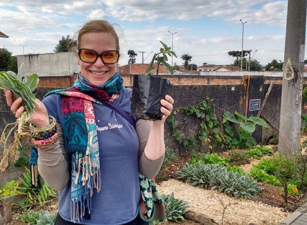 Moradora colhe alimentos plantados em espaço público (Foto: Reprodução/Facebook)