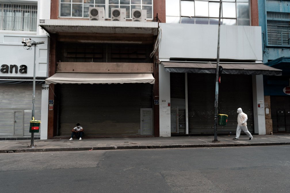 SÃO PAULO - Pessoas passam pela rua 25 de março, em São Paulo, com o comércio fechado nesta sexta-feira (20) para evitar a propagação do novo coronavírus — Foto: Marcelo Brandt/G1