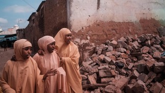 Meninas vestidas com uniforme escolar caminham ao lado de escombros ao longo de uma rua em Baidoa, Somália — Foto:  GUY PETERSON/AFP