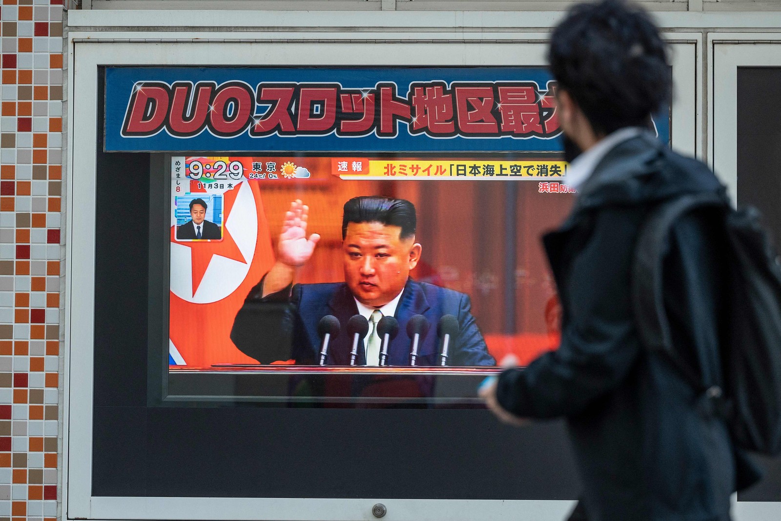 Homem passa por uma tela de TV que exibe notícia sobre o último lançamento de mísseis norte-coreanos, com imagens do líder do Norte, Kim Jong-Un, em Tóquio. — Foto: Richard A. Brooks / AFP