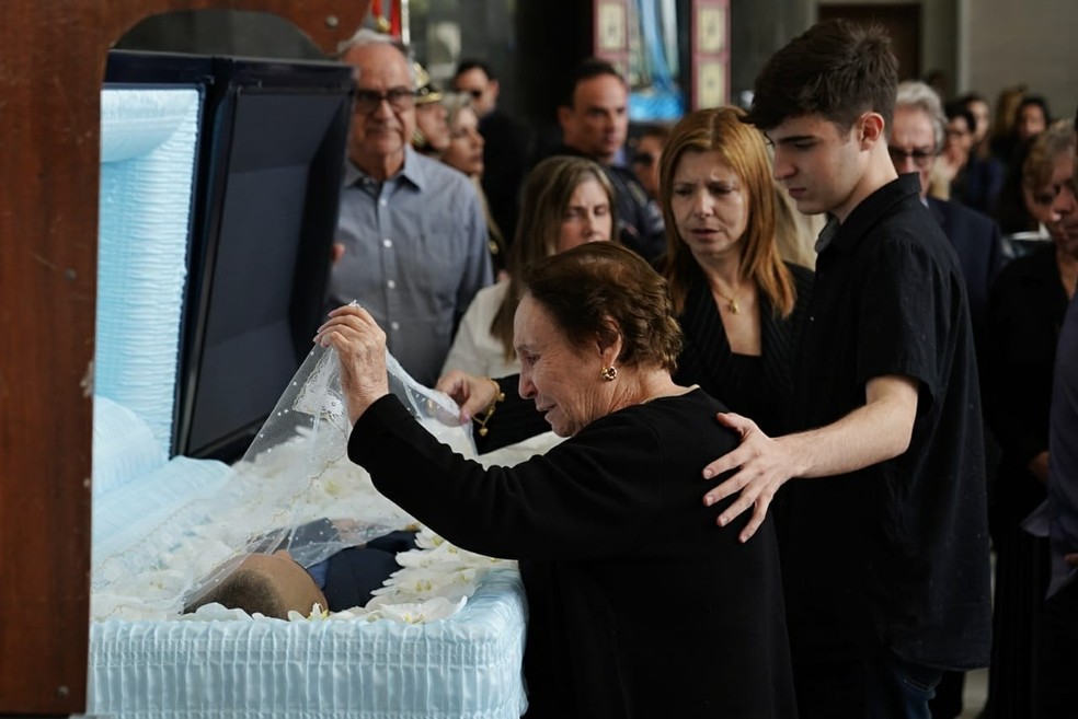 Mãe de Gugu, Maria do Céu, levanta véu que cobre corpo do filho. — Foto: Marcelo Brandt/G1