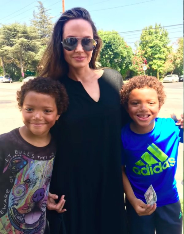 A atriz Angelina Jolie e os gêmeos que a venderam o brinquedo (Foto: YouTube)