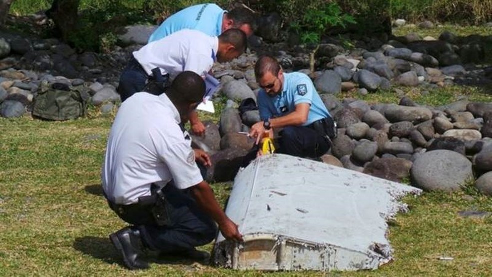 Em 2015, policiais franceses inspecionam um grande pedaço de destroços de avião encontrados na ilha francesa de La Reunion, no Oceano Índico — Foto: Reuters/Via BBC