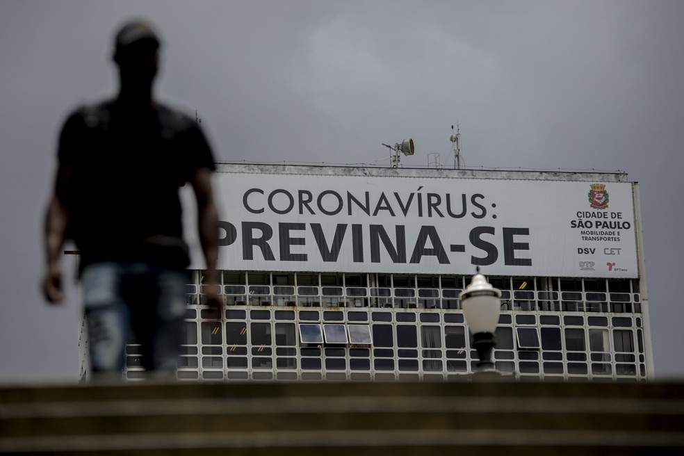 Pedestre passa por cartaz que pede prevenção contra o coronavírus, no Centro de São Paulo, em 2021 — Foto: Suamy Beydoun/Estadão Conteúdo