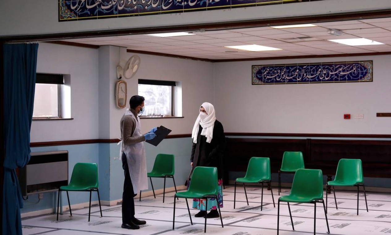 Uma mulher conversa com um trabalhador médico antes de receber a vacina Oxford / AstraZeneca no Al-Abbas Islamic Center, que foi convertido em um centro temporário de vacinação em Birmingham, região central da Inglaterra — Foto: DARREN STAPLES / AFP - 21/01/2021