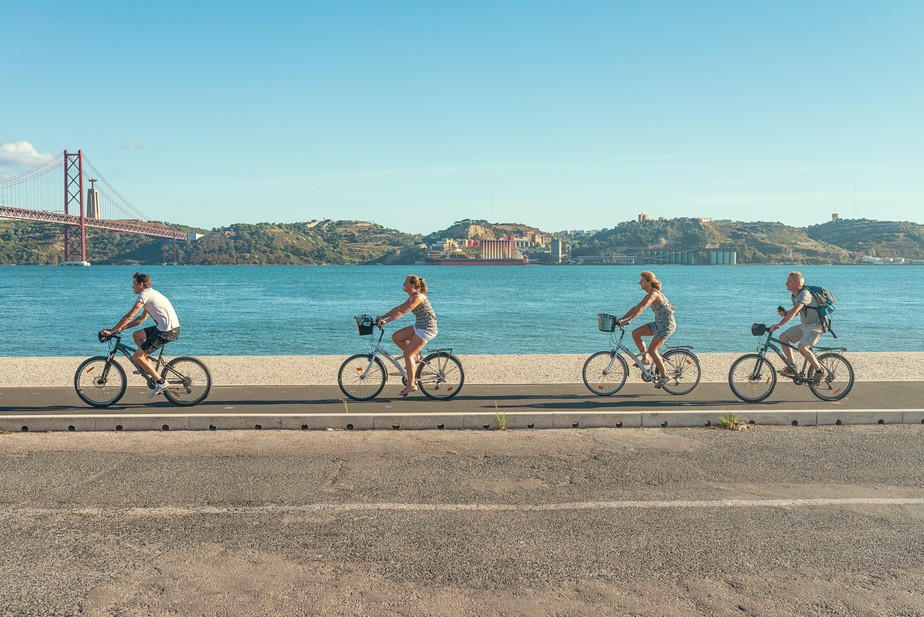 Ciclistas pedalam à beira do Rio Tejo, em Lisboa