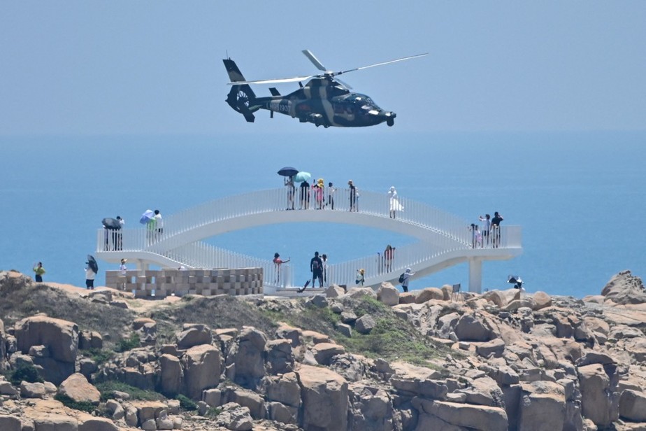 Turistas observam enquanto helicóptero militar sobrevoa sobre ilha Pigntan, um dos pontos da China mais próximos de Taiwan