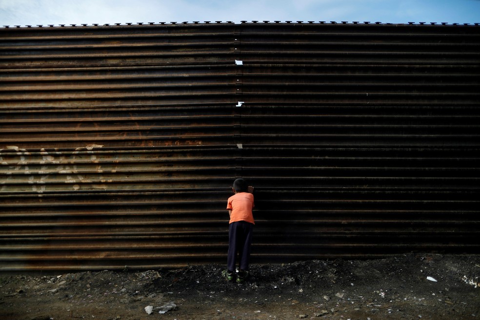 Um menino olha pelo buraco do atual muro na fronteira entre o México e os EUA em Tijuana, no lado mexicano (Foto: Edgard Garrido/Reuters)
