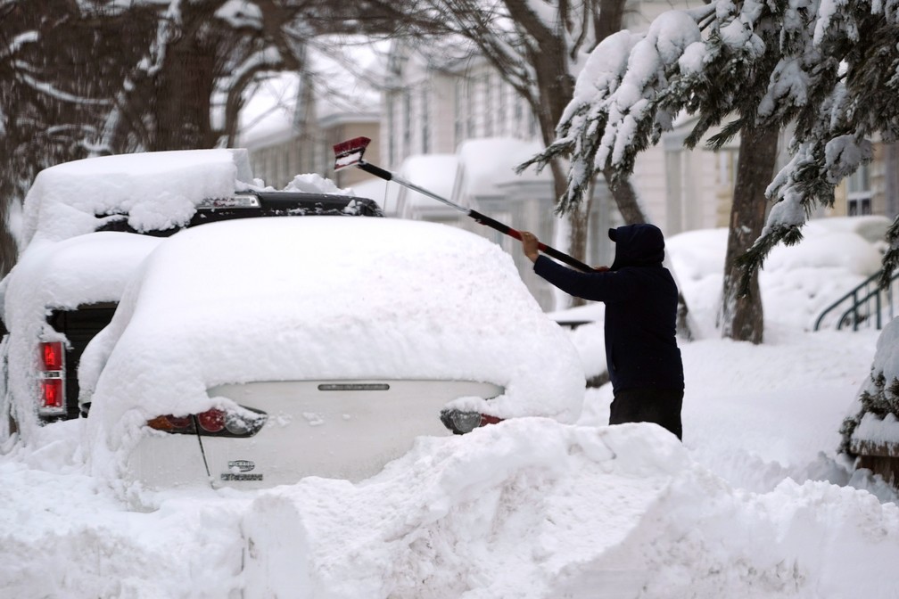 Homem tenta tirar grossa camada de neve em carro durante nevasca no nordeste dos EUA em 2 de fevereiro de 2021 — Foto: Elise Amendola/AP