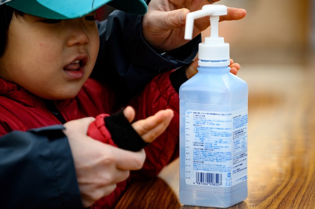 Mãe coloca álcool em mão de criança na cidade de Iwate, no Japão, em 23 de março de 2020 — Foto: Philip Fong/ AFP