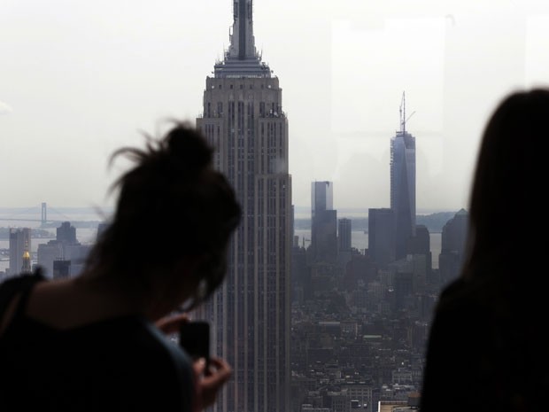Mulher tira foto do Empire State Building (à esq.) ao lado do One World Trade Center (centro) (Foto: Richard Drew/AP)