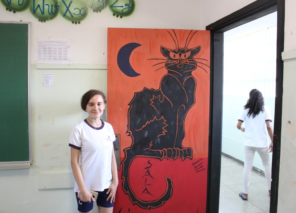 Danubia Pereira ao lado de sua reproduÃ§Ã£o da arte "Le Chat Noir", do designer ThÃ©ophile Steinlen. â Foto: Vitor Muniz/G1