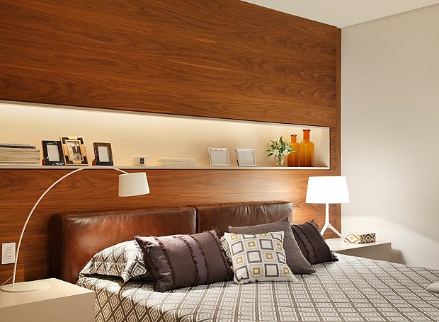 No quarto do morador, o painel de madeira faz as vezes de cabeceira com nicho para objetos de décor e porta-retratos (Foto: MCA Estúdio)