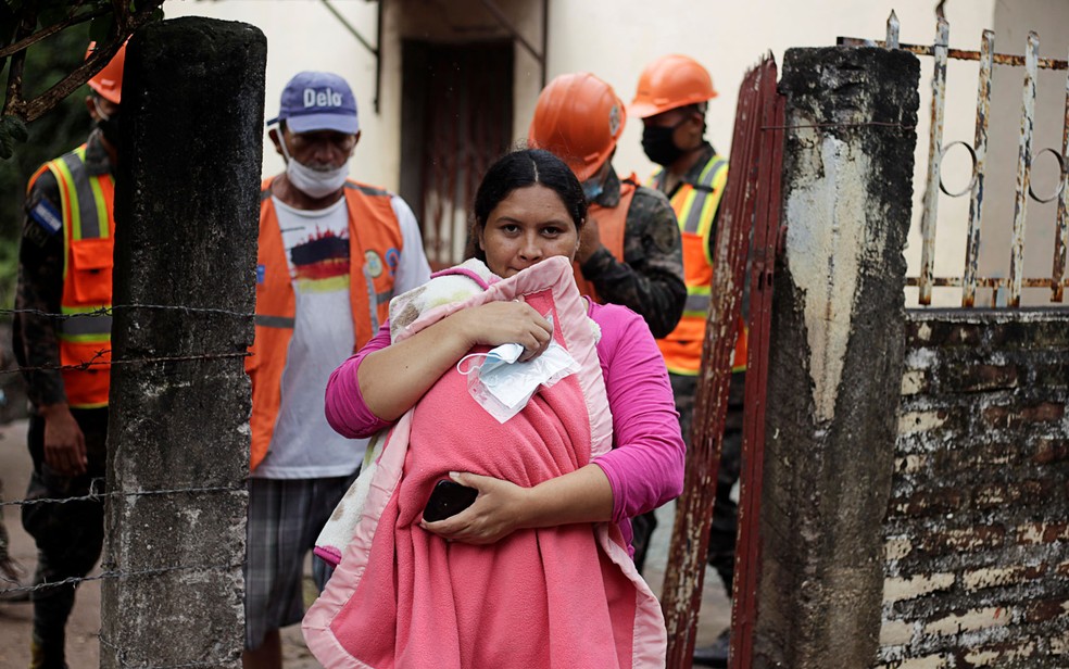 Mulher protege seu bebê enquanto soldados hondurenhos retiram moradores de área de risco por causa do furacão Iota, em Marcovia, na terça-feira (17) — Foto: Reuters/Jorge Cabrera 