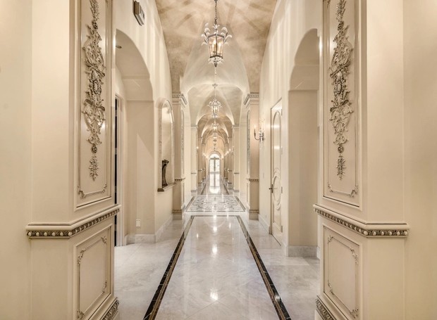 CORREDOR | Piso em mármore e paredes trabalhadas em gesso, claramente o local é inspirado em grandes palácios, como Versailles (Foto: Reprodução / MLS)