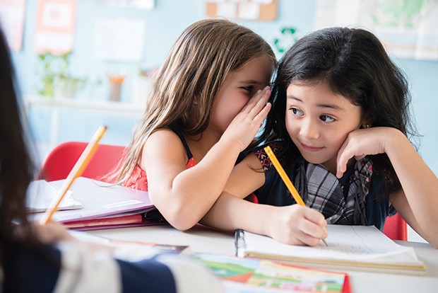 Girl whispering to classmate in school (Foto: Getty Images/Tetra images RF)