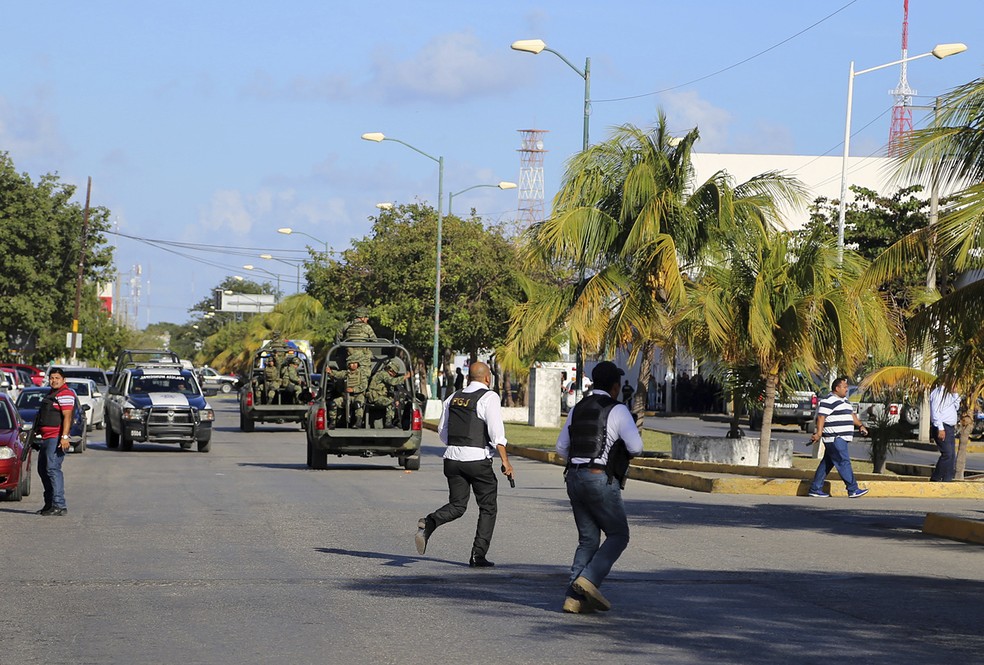 Policiais correm perto do prédio do Ministério Público após disparos nest terça-feira (17) em Cancún, no México (Foto: AP Photo)