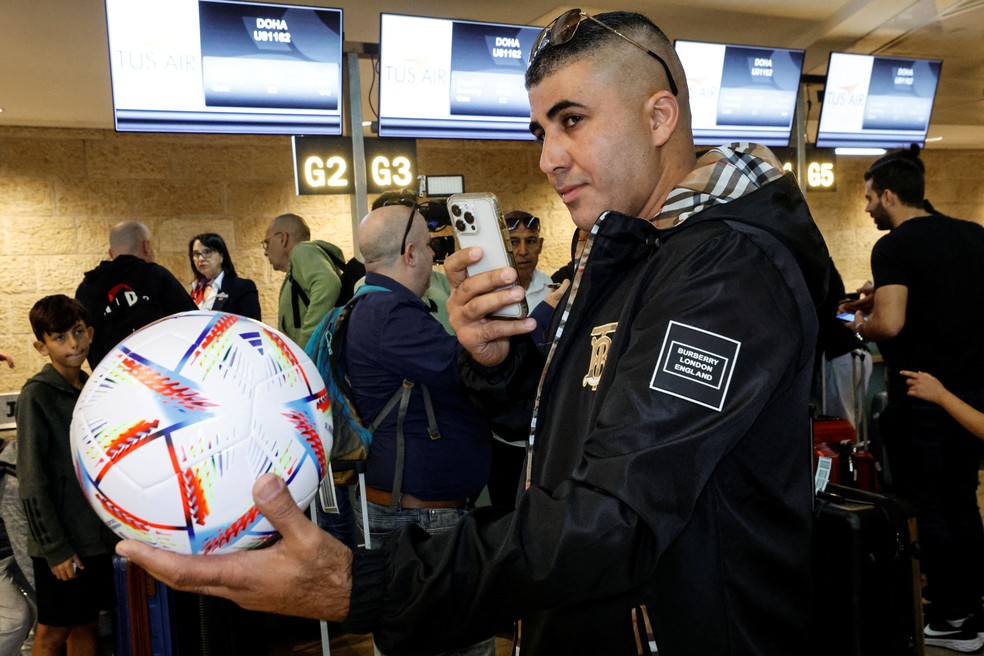 Passageiro do primeiro voo Tel Aviv-Doha segura bola no saguão do aeroporto da capital israelense enquanto espera na fila para embarcar, em 20 de novembro de 2022. — Foto: Amir Cohen/ Reuters