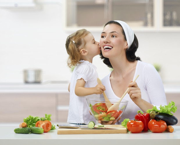 Mãe cozinha com a filha criança (Foto: Thinkstock)