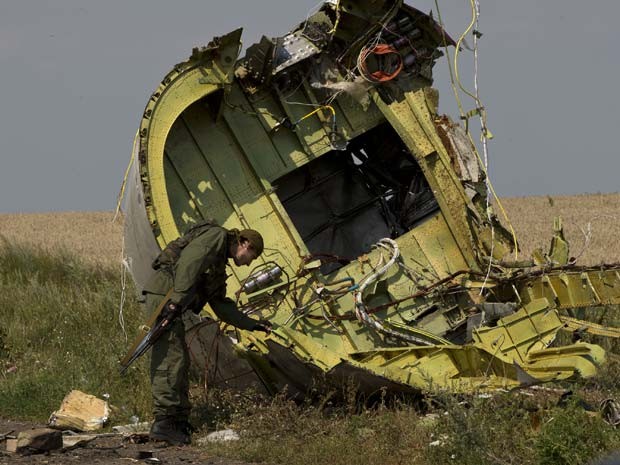 Um separatista pró-Rússia vê nesta terça-feira (23) destroço de avião malaio que caiu em área perto da vila de Hrabove, no leste da Ucrânia (Foto: AP Photo/Vadim Ghird)