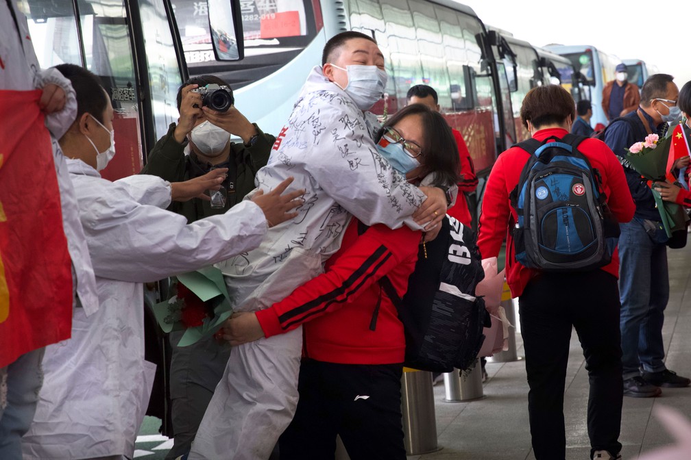 Médica da província de Jilin, na China, abraça colega de Wuhan enquanto se prepara para voltar para casa no Aeroporto Internacional Wuhan Tianhe, em Wuhan, nesta quarta-feira (8) — Foto: Ng Han Guan/AP