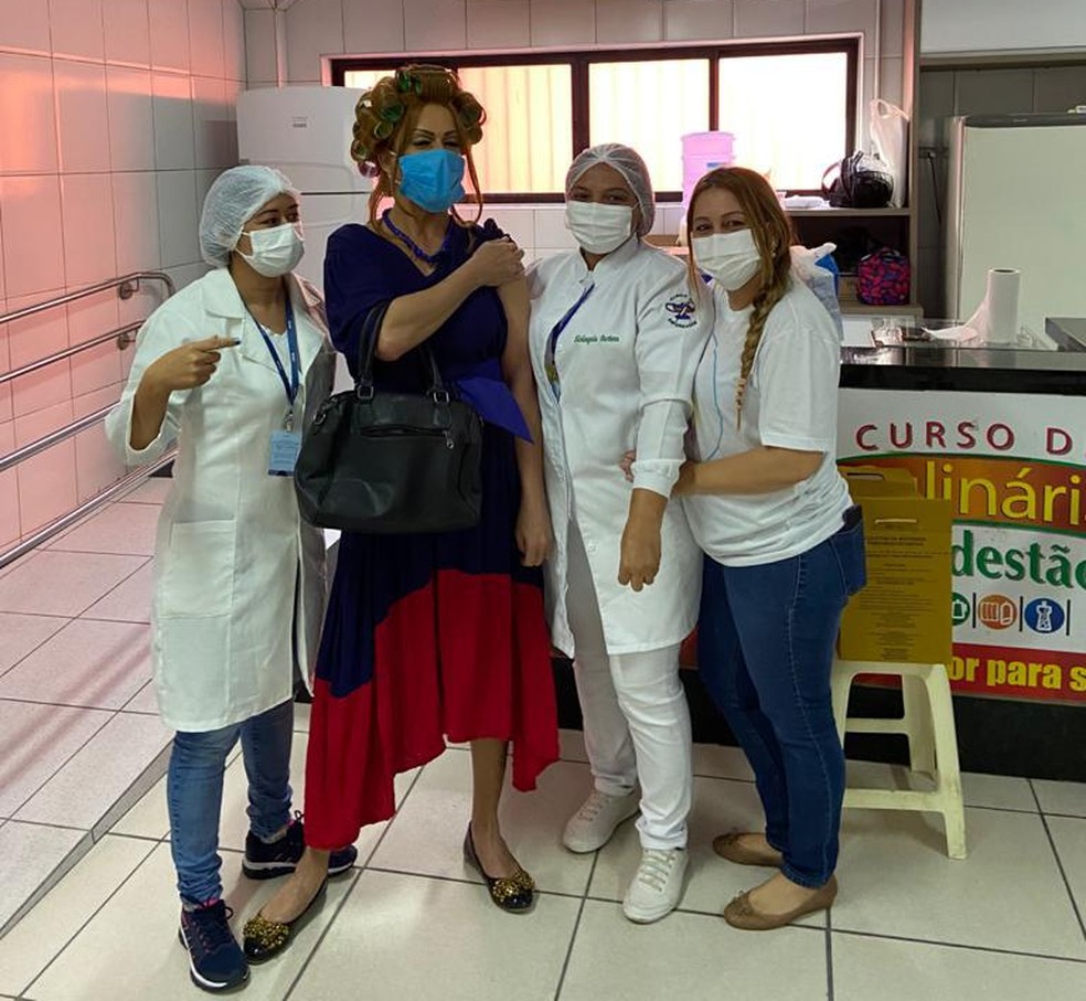 Flávio Costa, fantasiado de Dona Hermínia, tira foto com profissionais de saúde após tomar a vacina em Parnamirim, na Grande Natal. — Foto: Cedida