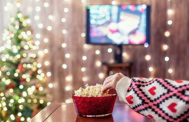 Christmas eve. Alone woman watching tv and eating popcorn. Home cinema. Cropped, close up (Foto: Getty Images/iStockphoto)