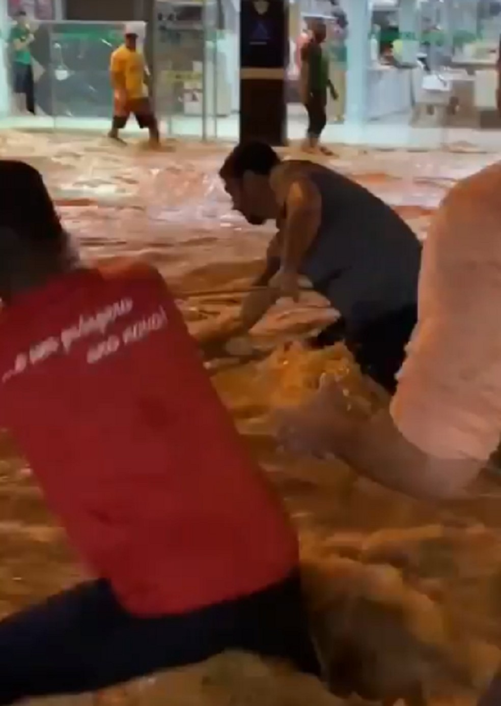 Em vídeos feitos por moradores, há imagens de um grupo tentando resgatar pessoas na correnteza formada no meio da rua — Foto: Reprodução/TV Gazeta