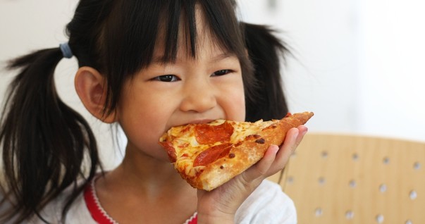 Criança comendo um pedaço de pizza (Foto: Shutterstock)