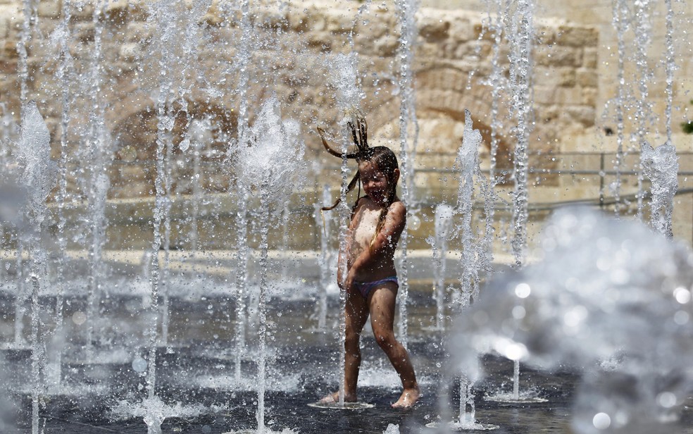 Uma menina brinca em uma fonte de Ã¡gua do lado de fora da Cidade Velha de JerusalÃ©m. A onda de calor em Israel atinge temperaturas de 45ÂºC (Foto:  Ronen Zvulun/Reuters)